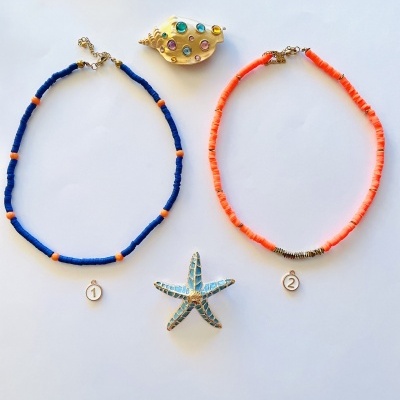 Dois colares coloridos com broches decorativos sobre fundo branco.