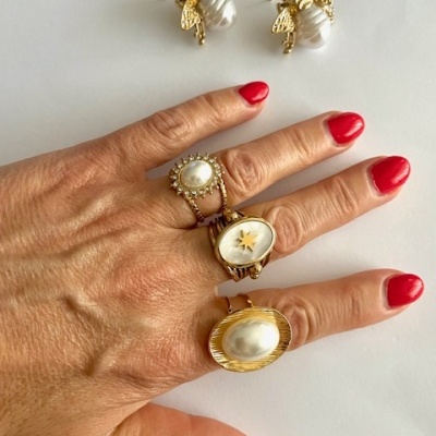 Joias douradas com pérolas e brincos de abelha sobre fundo branco