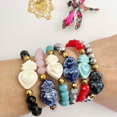 Pulseiras coloridas com corações decorativos e broche de libélula sobre fundo branco