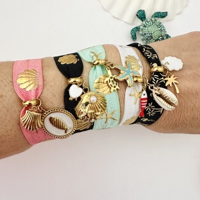 Pulseiras elásticas coloridas com pendentes marítimos e conchas ao fundo