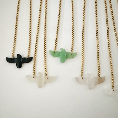Cinco colares dourados com pendentes em forma de pássaros em pedra preta, verde e branca.