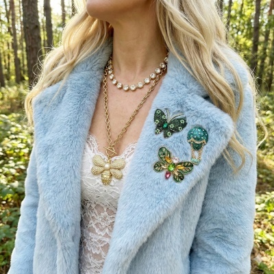 Casaco azul claro com broches coloridos e colares dourados