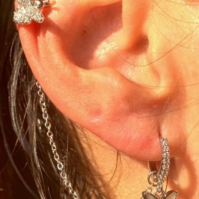 Brincos prateados com borboletas e corrente em orelha de mulher