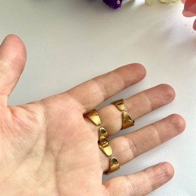 Anel dourado aberto na mão com flores ao fundo