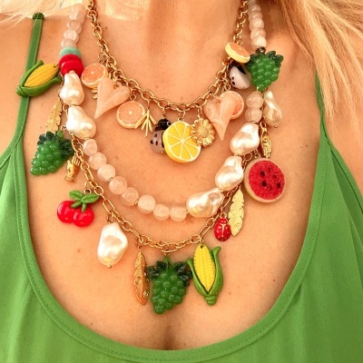 Colar com pingentes de frutas e folhas douradas sobre vestido verde