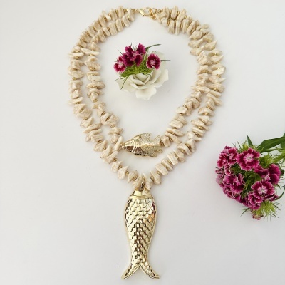 Colar com pedras bege e pingente de peixe dourado junto a flores artificiais roxas e brancas