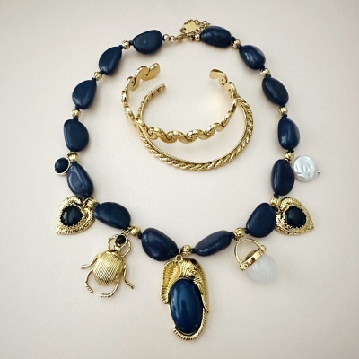 Colar azul escuro com pendentes dourados e braceletes dourados