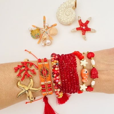 Pulseiras vermelhas e douradas com motivos marinhos no pulso