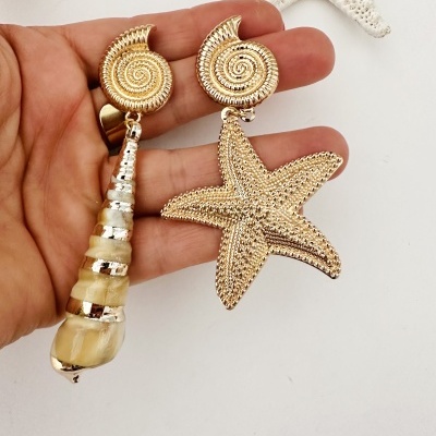 Brincos dourados, um com concha e outro com estrela do mar
