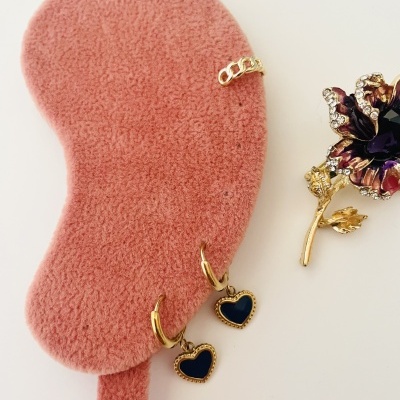 Brincos, anel e broche dourados com pedras, sobre base de veludo rosa