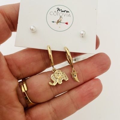 Brincos dourados com pendentes de elefante e dente num cartão Maria Cotovia