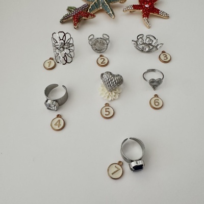 Anel de metal prateado com distintivos numerados e estrelas do mar decorativas com pedras brilhantes
