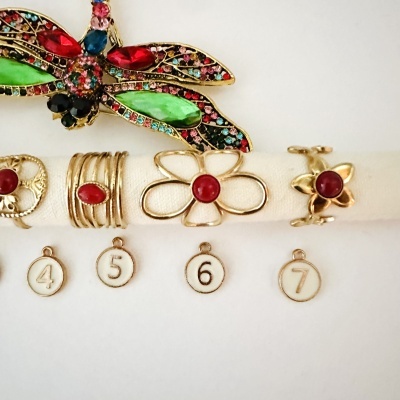 Anéis dourados com pedras vermelhas e decoração de libélula colorida