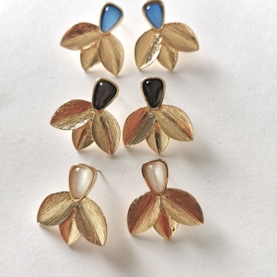 Três pares de brincos florais dourados com pedras coloridas em fundo branco.