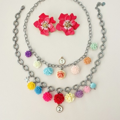 Conjunto de colares e brincos florais coloridos em fundo branco.