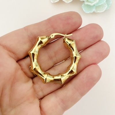 Brinco dourado em forma de argola com textura de bambu