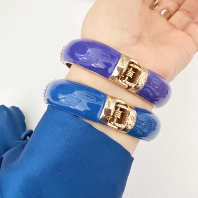 Pulseiras esmaltadas azul e roxa com fechos dourados no pulso.