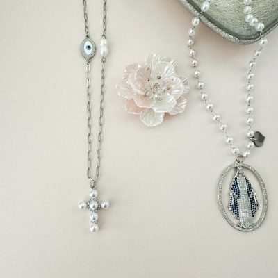 Colares e broche com pérolas e medalha prateada sobre fundo claro