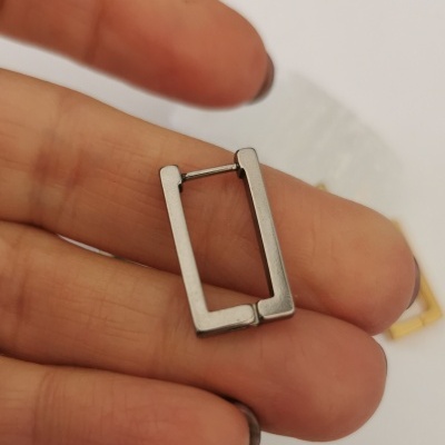 Argola quadrada de metal prata entre dedos
