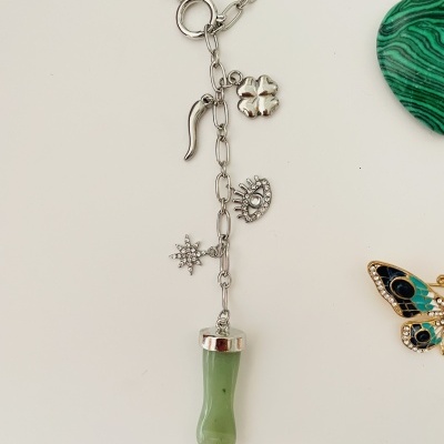 Colar prateado com vários pendentes incluindo trevo, olho, corno, estrela e pendente verde