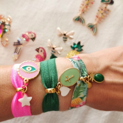 Pulseiras coloridas em tecido com pendentes dourados e fundo com brincos coloridos