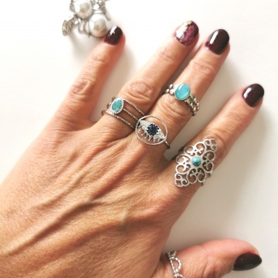 Mão com anéis prateados decorativos e unhas pintadas em fundo branco