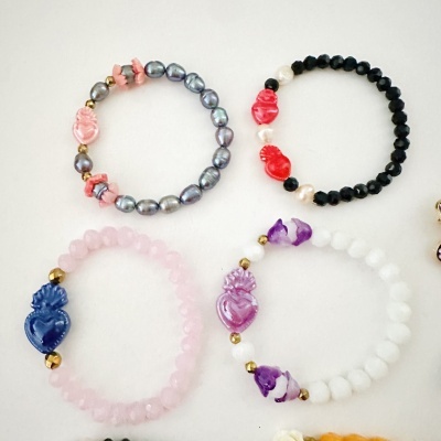 Quatro pulseiras elásticas com corações decorativos em várias cores e contas diversas.