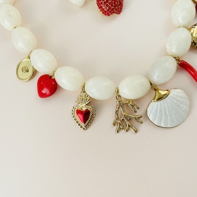 Colar com contas brancas e pingentes dourados e vermelhos sobre fundo claro
