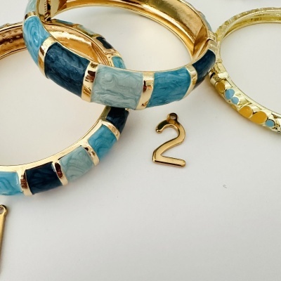 Três pulseiras douradas com esmalte azul e amarelo e peça pendente número 2