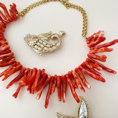 Colar com contas vermelhas alaranjadas e pendente de peixe dourado com pedras e pérola