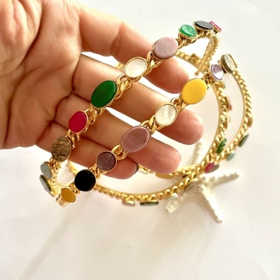 Pulseira dourada com pedras ovais coloridas em fundo branco