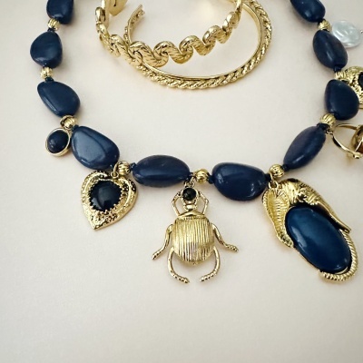 Colar azul com pendentes dourados e pulseiras douradas texturizadas.