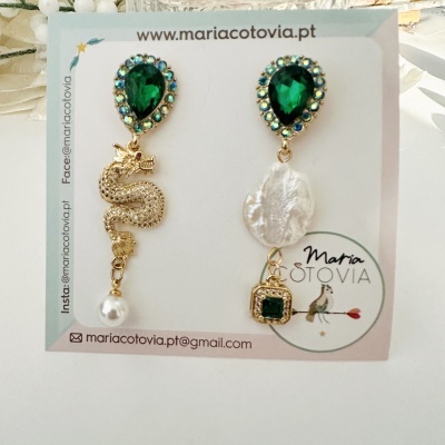 Par de brincos assimétricos com pedras verdes e detalhes dourados em cartão de apresentação
