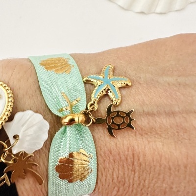 Pulseira azul claro com estampas douradas e pendentes em forma de estrela do mar e tartaruga