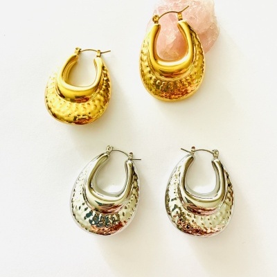 Conjunto de quatro brincos argola dourados e prateados com textura martelada sobre fundo branco e pedra rosa