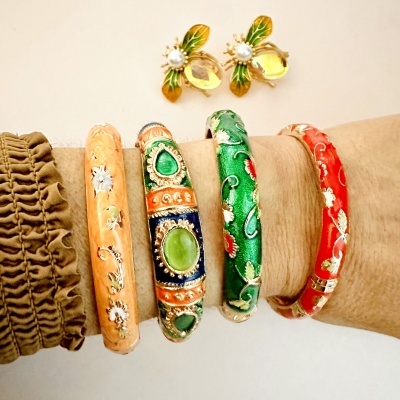 Pulseiras coloridas e brincos de abelha em pulso com fundo branco.