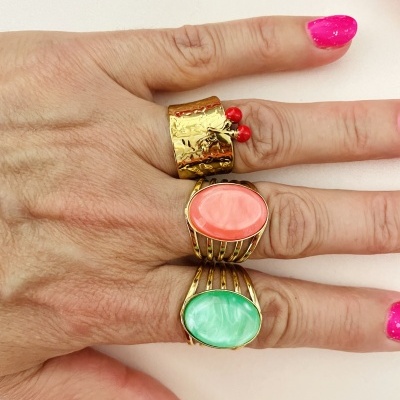 Mão com três anéis dourados e unhas rosa