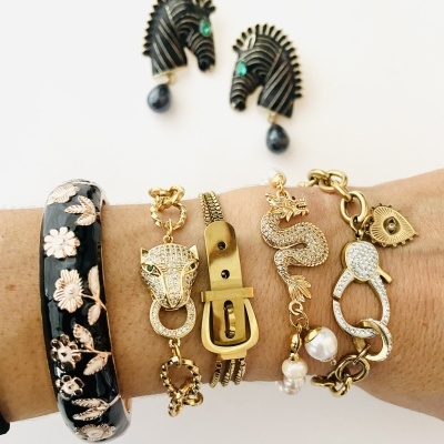 Pulseiras douradas e preta com flores e brincos de zebra