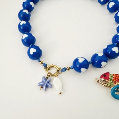 Pulseira azul com contas de corações brancos e vários pingentes do mar