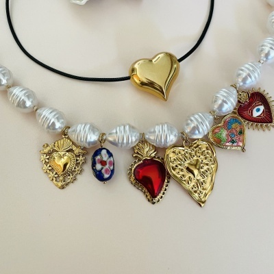 Colar de pérolas com pendentes coloridos e cordão preto com coração dourado.