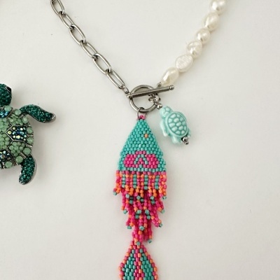 Colar com corrente prateada, pérolas brancas e pendentes em forma de tartaruga e padrão de contas coloridas