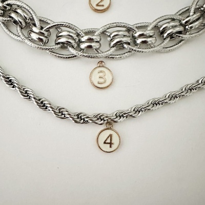 Dois colares prateados entrelaçados com pendentes numerados 3 e 4