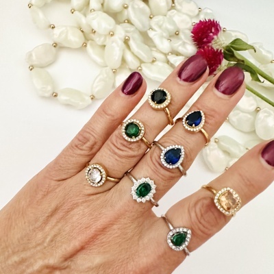 Mão feminina com anéis diversos coloridos e flores sobre fundo branco