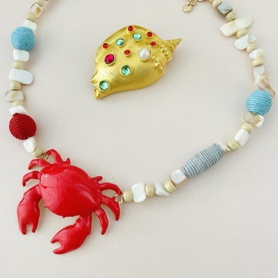 Colar com pendentes de caranguejo vermelho e concha dourada com pedras coloridas