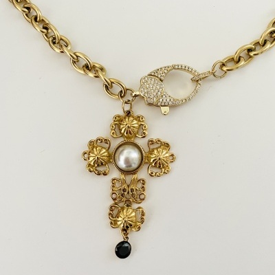 Colar dourado com pendente em forma de cruz decorada com flores, pérola e pedra preta