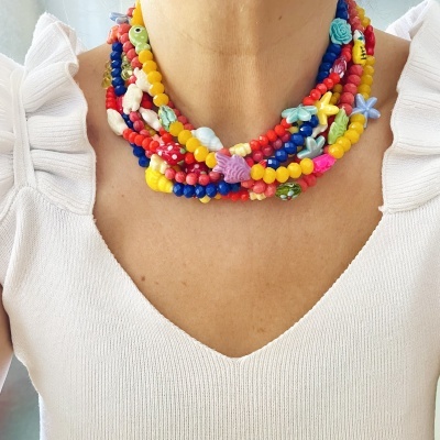 Colar colorido multicolorido de contas e figuras distintas usado com blusa branca de manga franzida