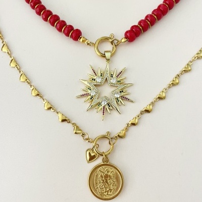 Dois colares, um vermelho com pendente estrela dourada e outro dourado com corrente de corações e pendente redondo.