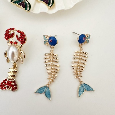 Brincos com design de peixes em dourado, azul e vermelho com pérolas.