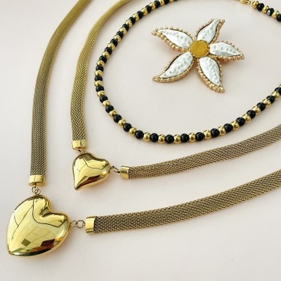 Conjunto de joias com colar e pulseira dourados com corações e colar de contas pretas com estrela de mar branca e amarela