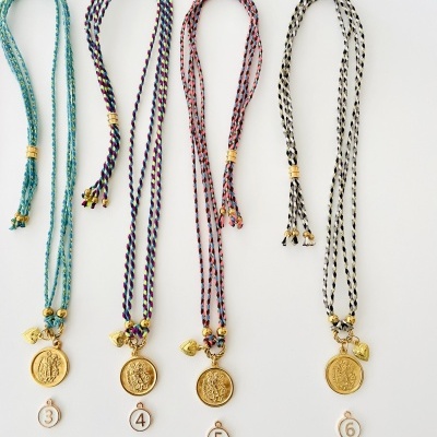 Quatro colares coloridos com medalhas douradas em fundo branco